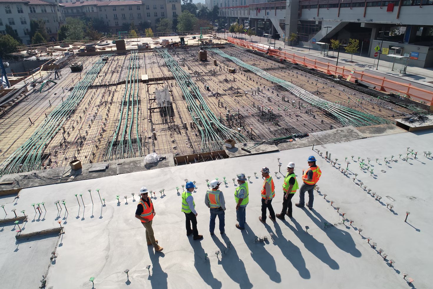 DSM Empreendimentos: Homens com coletes verdes e laranjas observando obra de cima pra baixo